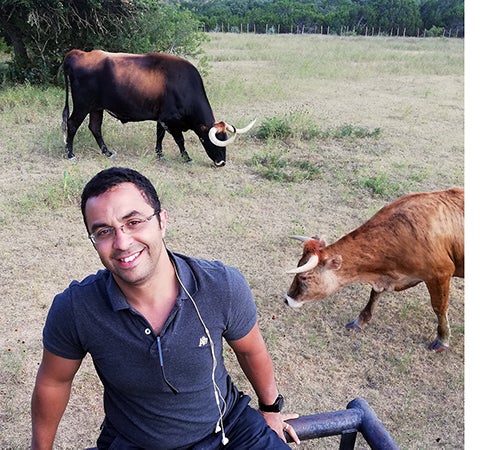 mohamed stands next to longhorns in texas