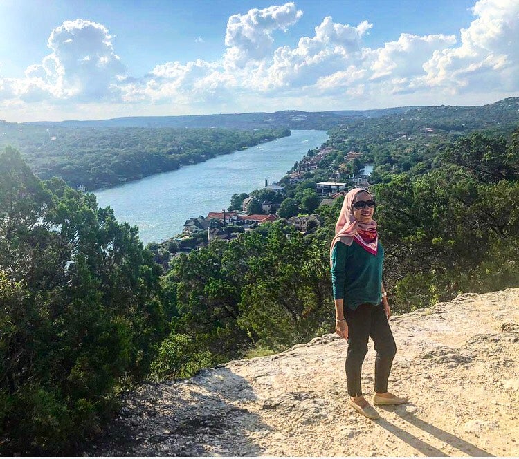 Sahar stands on a cliff overlooking the river in Austin, Texas