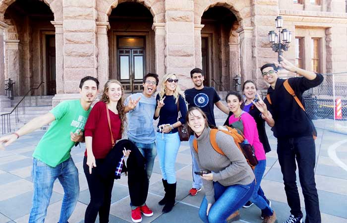 Group of international students smiling and posing with the hook'em sign.