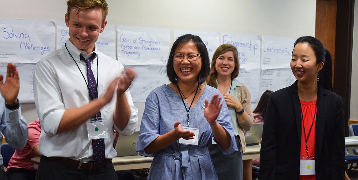 The seminar group plays the name game—clapping at each person in the circle while saying their name—to get to know each other on the first day of the conference.
