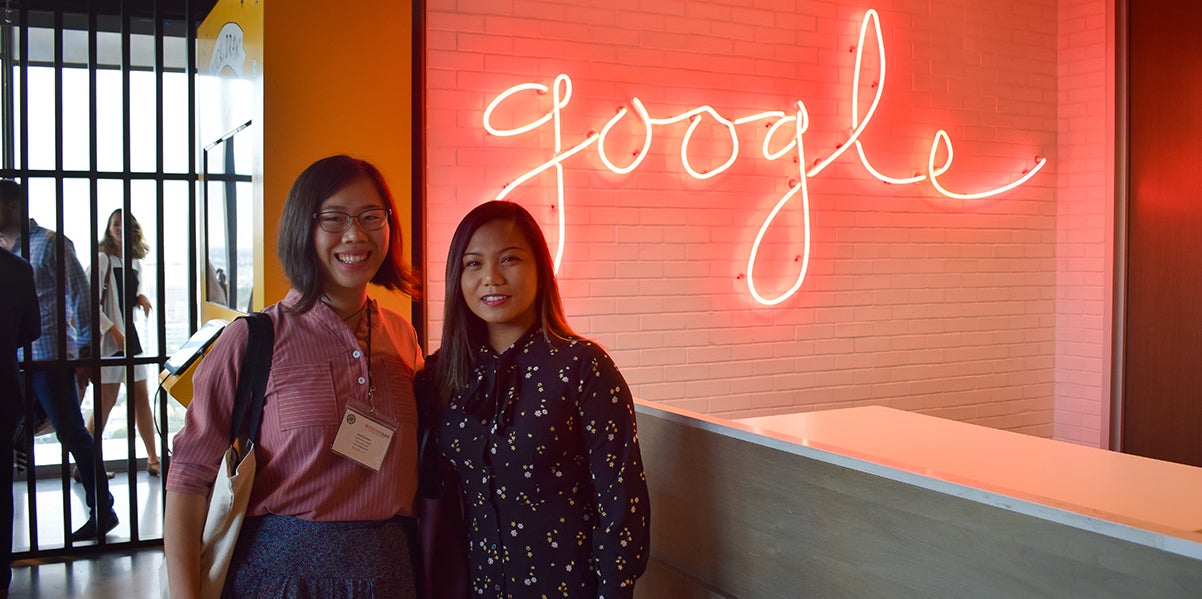 Two alumnae pose with the Google logo before their tour of the site
