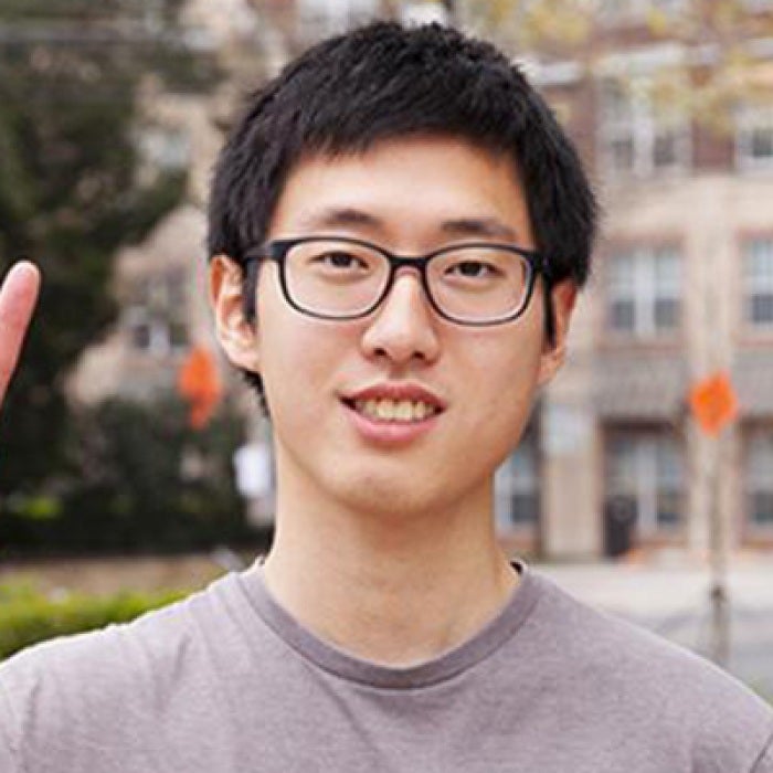 Exchange Student Chen Pang Chang gives the hook 'em horns sign while standing in front of the Texas Global building.