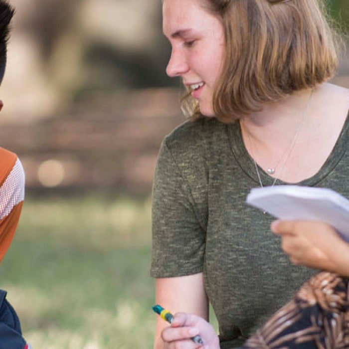 Three students of diverse ethnicity study together on the campus grounds