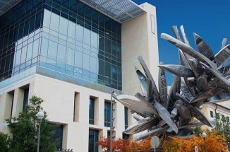 white and glass building next to sculpture of metal canoes during daytime