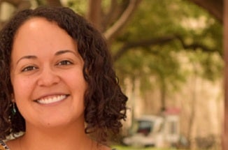 Professor Mónica A. Jiménez smiles in front of the Barbara Jordan statue on UT Austin's campus.