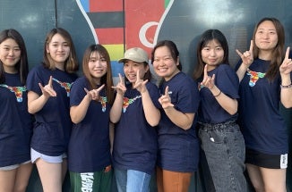 Students from Ritsumeikan Asia Pacific University throw a "Hook 'em Horns"