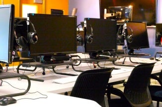 Computer monitors and headphones in Moody College's multimedia classroom