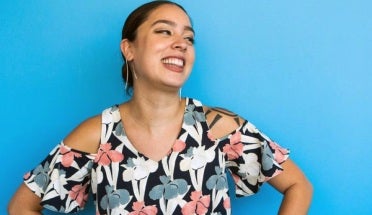 Jessica Natalia stand smiling against a light blue wall 