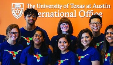 Education Abroad Peers pose for a picture in front of the International Office Logo 