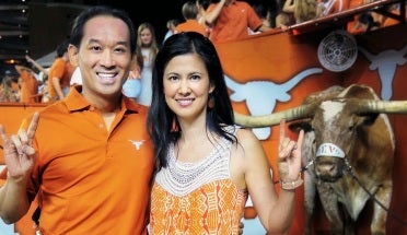 andrew vo stands with wife sophie at a texas game