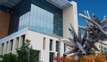 white and glass building next to sculpture of metal canoes during daytime