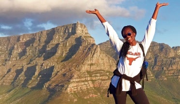 a student poses on a mountain and smiles
