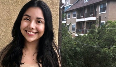 clarissa stands in front of a beige wall and smiles 
