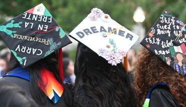 Three Latinx UT Austin graduates wearing decorated mortarboards