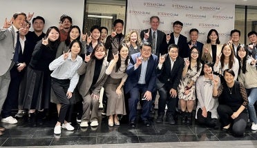 UT Austin Korean Alumni Association members throw Hook 'em horns