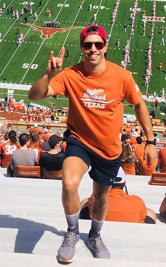 Student dressed in orange poses in stadium at football game