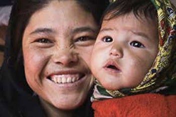 An Afghan mother smiles with her infant