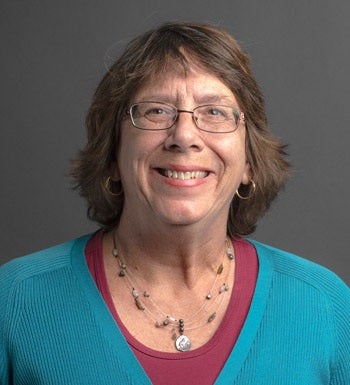 English Language Center instructor Ellen Butki smiles in a red top with turquoise sweater